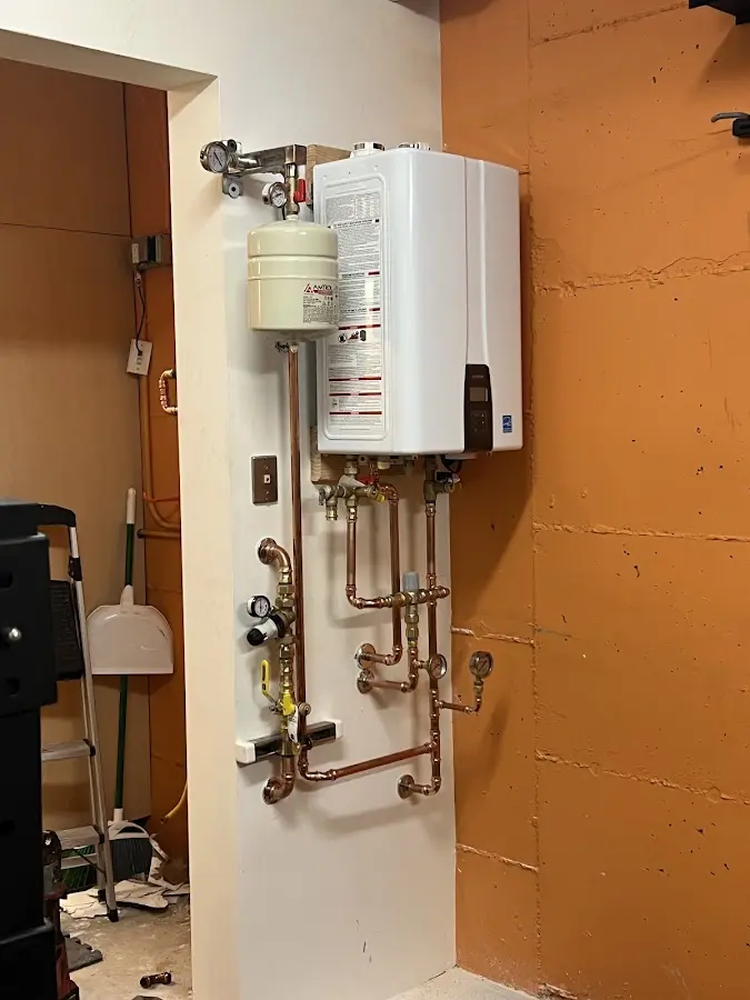 Plumbing technician inspecting water heater connections in Tyro